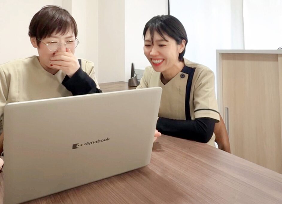 訪問看護ステーションすこやかのスタッフが笑顔でパソコンを覗き込む様子